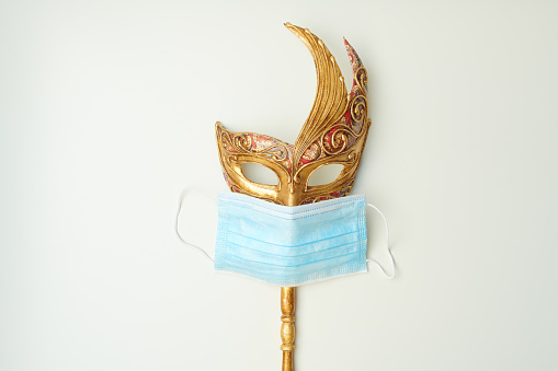 covid flat lay with venetian mask and medical mask on white background.