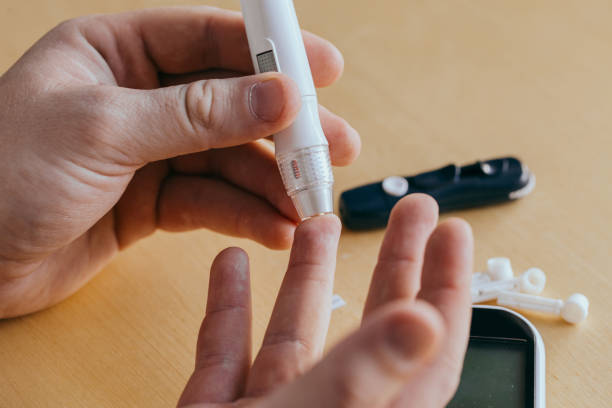 istock Man taking a blood sample with a lancet handle indoors. Diabetes concept 1278812594