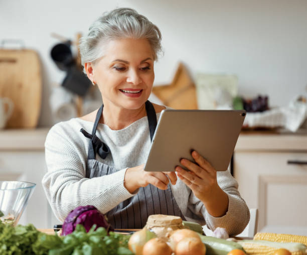 istock Happy mature woman using tablet while cooking at home 1278814073