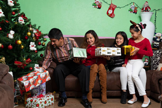 Family pitting gift boxes under a christmas tree Family of four putting gift boxes under a christmas tree 12 17 months stock pictures, royalty-free photos & images