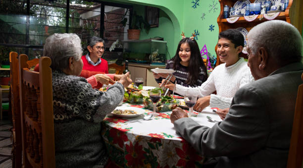 Family at a Christmas dinner Family at christmas dinner, dressed in christmas sweaters, talking and smiling while having dinner together 80 89 years photos stock pictures, royalty-free photos & images