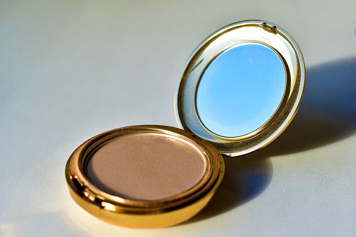 Gold round compact with mirror on white background