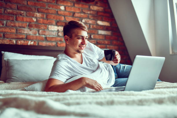 istock Male Watching Movie And Drinking Coffee In Bed 1278826457