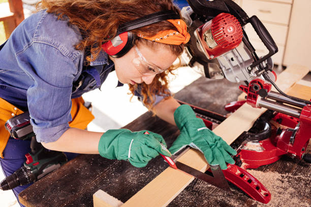 istock Young female carpenter with a miter saw. 1278828220