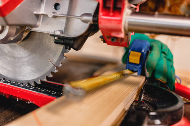 istock Female carpenter hands with board and miter saw. 1278828289