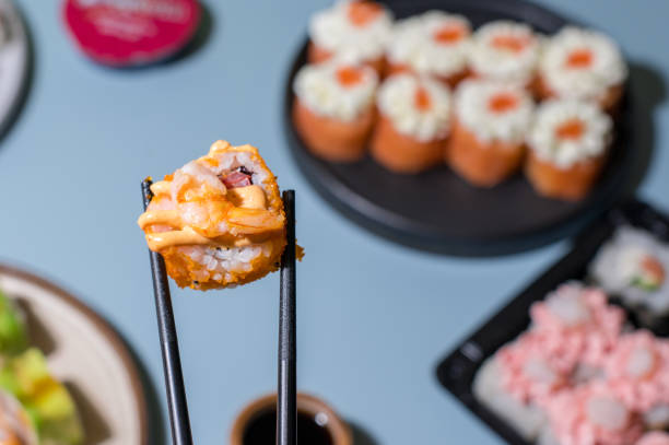 суши, установленные на синем фоне. крупным планом суши рулонах с палочками - chopsticks soybean japanese cuisine blue стоковые фото и изображения