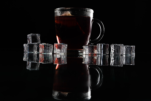 Photographing the product - tea in a cup on a black background. With ice cubes