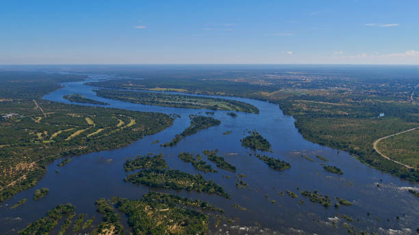 Aerial panorama view of Zambesi River delta ahead of Victoria Falls, bush land and village Livingstone in the background. stock photo