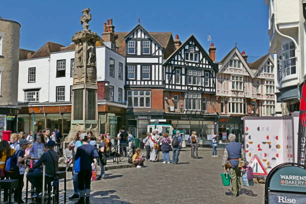 Canterbury Kent. High street and cathedral Canterbury Kent England May 2019. Busy street scene in narrow street of three story houses some half timbered. street winds and narrows to right and more houses in distance. Entrance to the Cathedral and main square Blue sky canterbury uk stock pictures, royalty-free photos & images