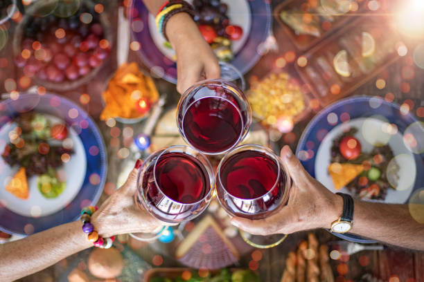 family dinner for a celebration with red wine and cheers. - dinner friends christmas imagens e fotografias de stock
