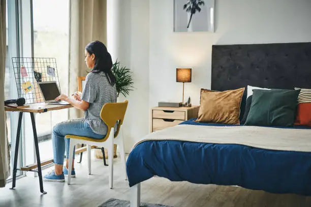 Shot of a young woman cleaning her laptop while working from home