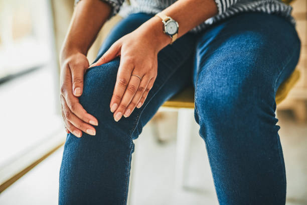 Sitting all day can cause tightness around your joints Closeup shot of an unrecognisable woman rubbing her knee in pain while working from home knee stock pictures, royalty-free photos & images