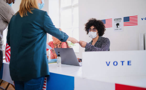 people with face mask voting in polling place, usa elections and coronavirus. - jovens a votar imagens e fotografias de stock
