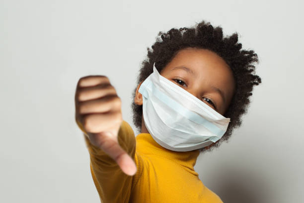 istock Black kid in medical protective face mask showing thumbs down on white 1278839823
