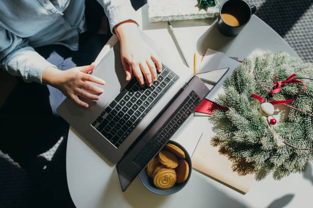 istock Working in a Cozy Christmas Setting: Hands of a Woman Using her Laptop Computer at Home 1278843080