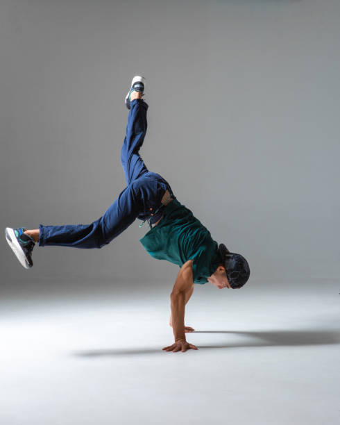 istock Cool guy breakdancer dances on the floor standing on hands isolated on gray background. Breakdance lessons 1278844340