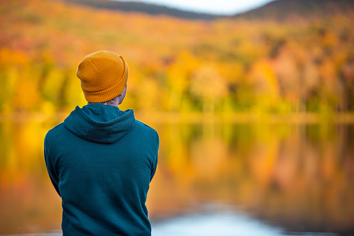 Young peaceful man out in nature alone reflecting on a vibrant autumn scene.