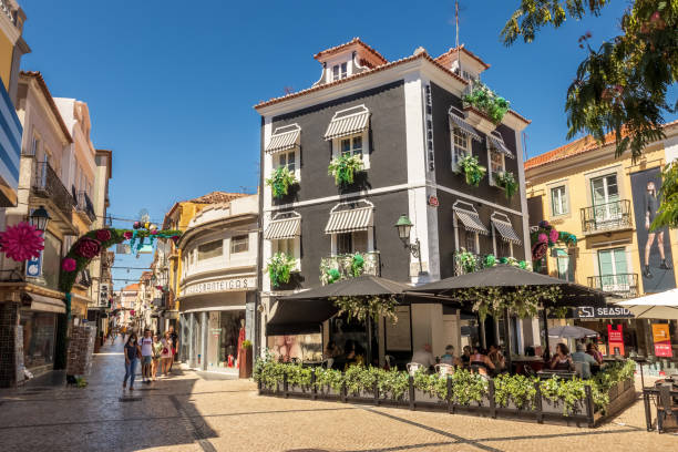 Shopping street in the downtown of Setúbal in Portugal, with a beautiful building full of flowers on a summer morning. Setúbal, Portugal - August 28, 2020: In downtown Setúbal we find a large part of traditional commerce, where world brands join other older ones, as well as bars and restaurants as in the case of the building depicted in which a restaurant bar operates. setúbal city portugal stock pictures, royalty-free photos & images