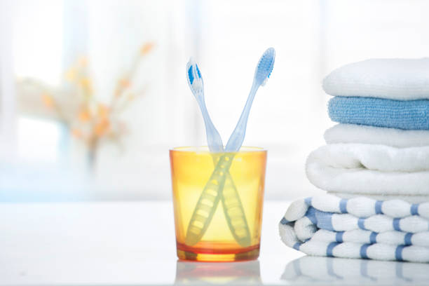 Tooth brushes and towels stack in bathroom.Tothbrush in glass on table empty copy sapce.