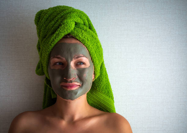 istock Young woman with clay mask on her face against light background, space for text. 1278851759