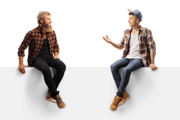 istock Male teen student sitting on a blank panel and talking to a bearded guy 1278853224