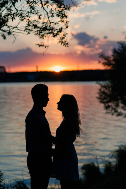 istock Couple in love back light silhouette at lake orange sunset 1278856496