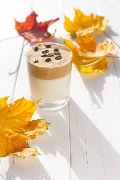 Traditional Korean caffeinated milk drink, Dalgona coffee in a glass with coffee beans on a white board background.