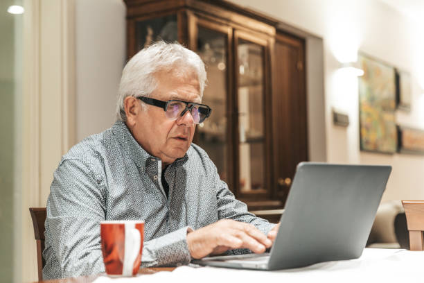istock Senior man surfing on a laptop computer at home 1278856792