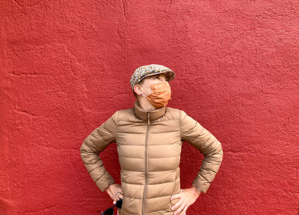 istock Woman Wearing Orange Mask, Red Background 1278857619