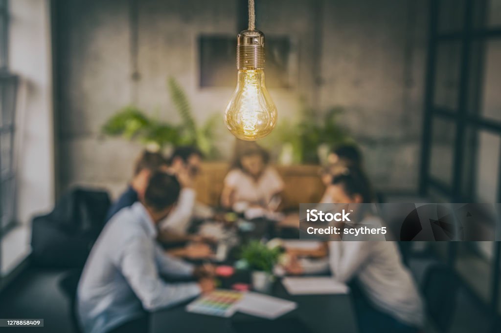 Young creative business people meeting at office. Young business people are discussing together a new startup project. A glowing light bulb as a new idea. Teamwork Stock Photo