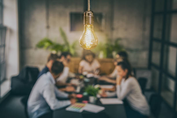 Young creative business people meeting at office. Young business people are discussing together a new startup project. A glowing light bulb as a new idea. marketing stock pictures, royalty-free photos & images