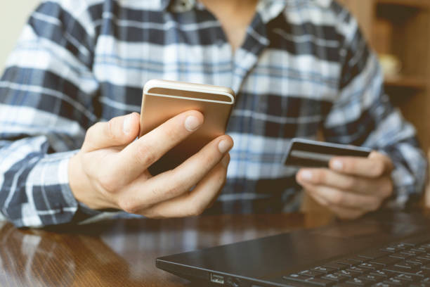 istock Man's hands holding a credit card and using a smart phone for online shopping 1278859971