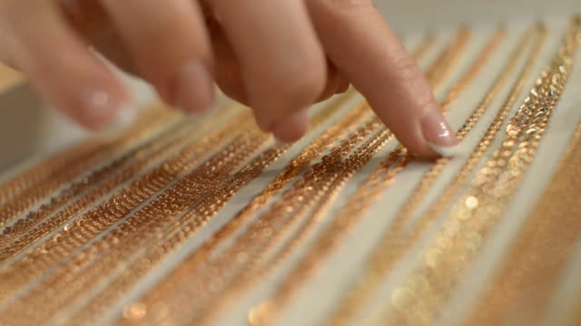 woman chooses the golden chain with her index finger.