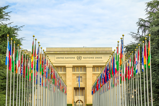 Geneva, Switzerland - Aug 16, 2020: Row of flags at entrance of United Nations Offices or Palais des Nations in Ariana Park, on shore of Lake Geneva. Since 1966 is main European headquarters of UN.