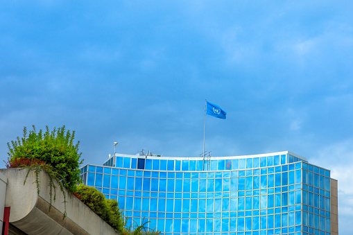 Geneva, Switzerland - Aug 16, 2020: blue skyscraper of WIPO, the World Intellectual Property Organization of the United Nations, located in Geneva city. UN flag on the top of skyscraper.