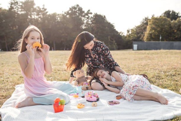 istock Mother two daughters and teddy bear having fun in park 1278869724