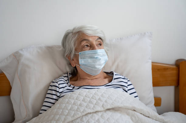 istock Senior woman in bed wearing a facemask to avoid COVID-19 1278870372