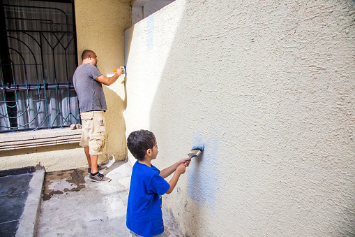 Father and son painting backyard wall