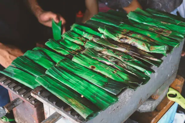Photo of Cooking or Grilling of traditional local food otak otak in Indonesia. Made from grilled fish cake parcels from Betawi, Jakarta.