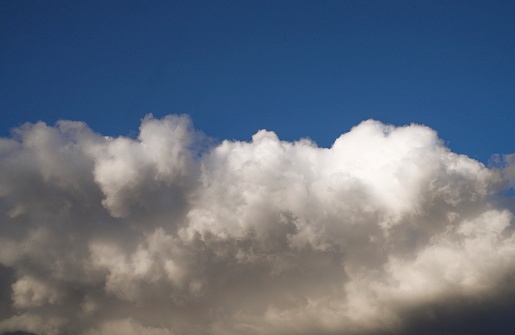 This image shows a dark blue sky covered with large white clouds.