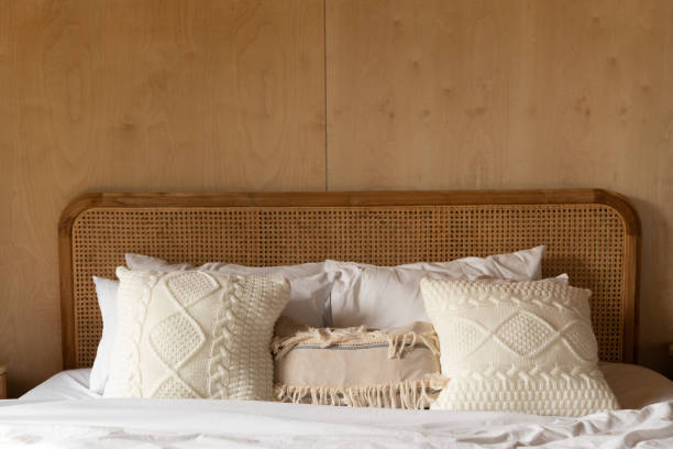 istock Stylish Bedroom corner with rattan headboard and bed with soft white pillows setting with  plywood wall on the background / cozy interior design / copy space 1278895082