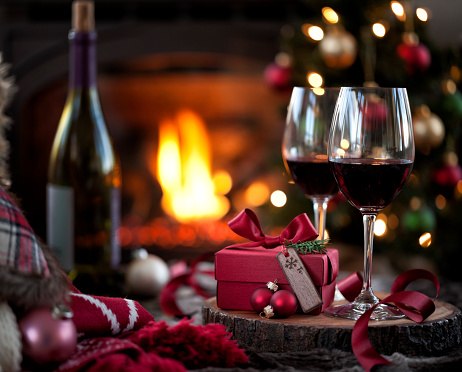 Christmas red wine and a gift in front of a fireplace. Very shallow depth.