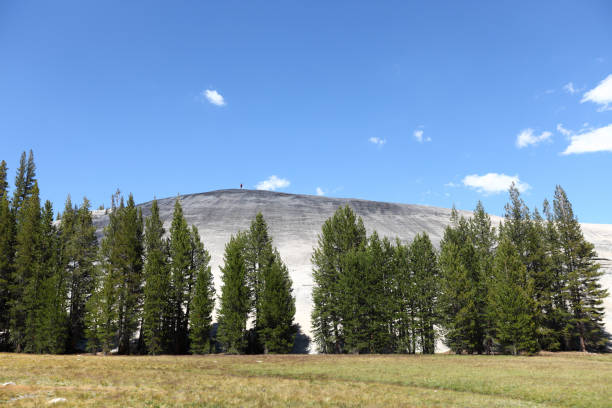 Yosemite National Park, the Pothole Dome with man hiking on top for scale. Beautiful summer day in Yosemite, California, USA.