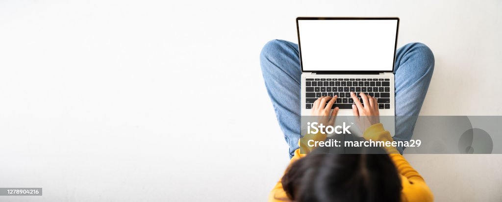 Top view of woman sitting on floor and using laptop blank screen white background. Mockup, template for your text, Clipping paths included for device screen. Panoramic image with empty copy space Laptop Stock Photo