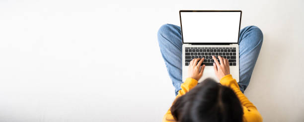 頂部視圖的女人坐在地板上,並使用筆記型電腦空白螢幕白色背景。類比,文字的範本,設備螢幕的剪切路徑。帶空白複製空間的全景圖像。 - 手提電腦 圖片 個照片及圖片檔