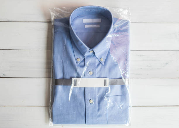 istock Blue shirt folding in plastic package on white wooden background. 1278904294