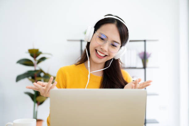 istock Young asian woman in headphone having conversation chatting while using laptop at house. Work at home, Video conference, Online meeting video call, Virtual meetings, Remote learning and E-learning 1278904327