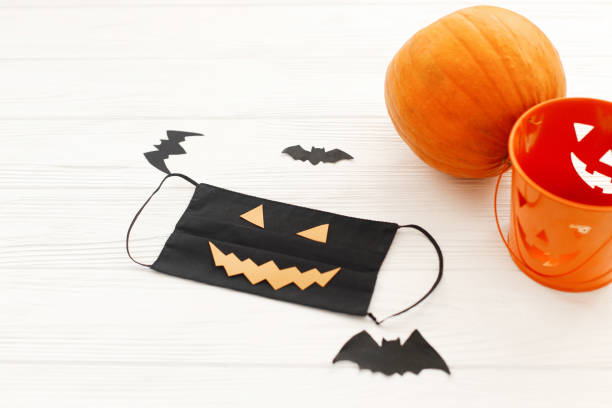 istock Evil face mask, pumpkin, jack o lantern pail, bat and spider decorations on white wood 1278905581