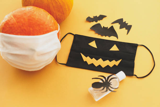 istock Halloween 2020 safe creative celebration. Evil face mask, pumpkin in mask, disinfection gel bottle 1278906590
