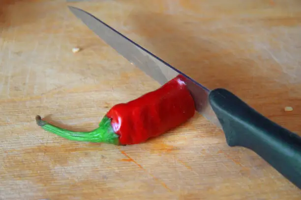 Red hot pepper on the wooden cooking desk and sharp knife on the kitchen